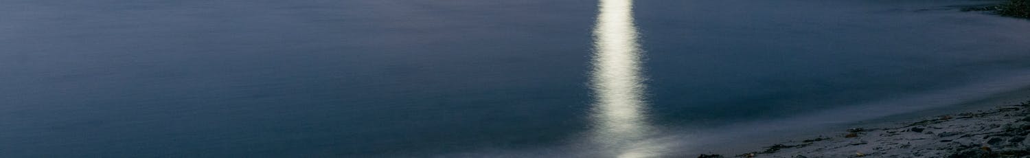 Bild av kustlinje och livräddartorn i fullmåne